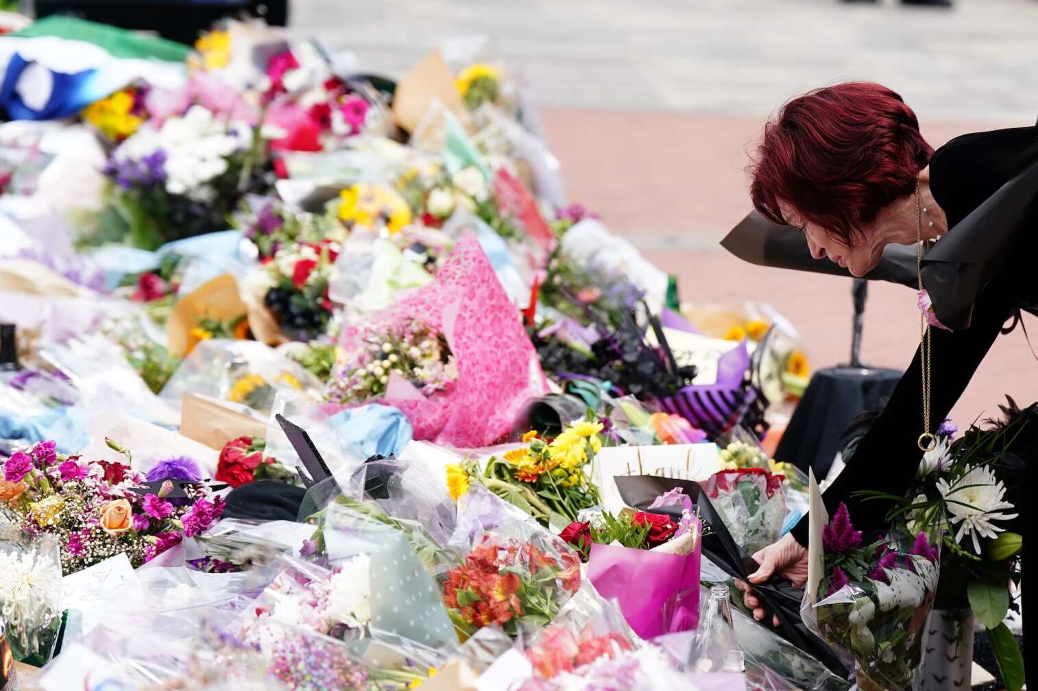 30.07.2025, Großbritannien, Birmingham: Sharon Osbourne legt zum Gedenken an den Black-Sabbath-Frontmann Ozzy Osbourne Blumen an der Black-Sabbath-Brücke in der Broad Street in Birmingham nieder, als sein Leichnam nach seinem Tod im Alter von 76 Jahren in der vergangenen Woche in seine Heimatstadt überführt wurde. Foto: Jacob King/PA Wire/dpa +++ dpa-Bildfunk +++